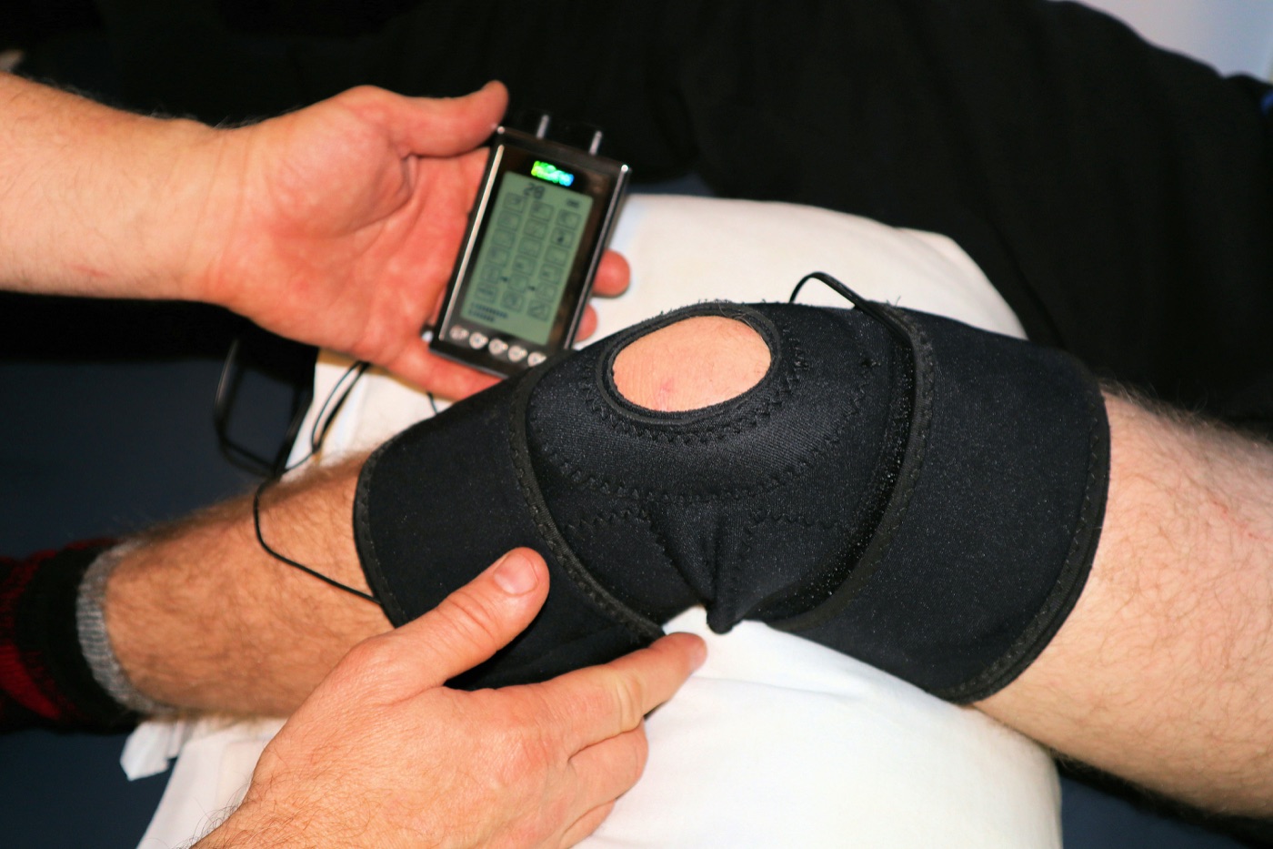 Therapist fitting a knee brace with a TENS unit
